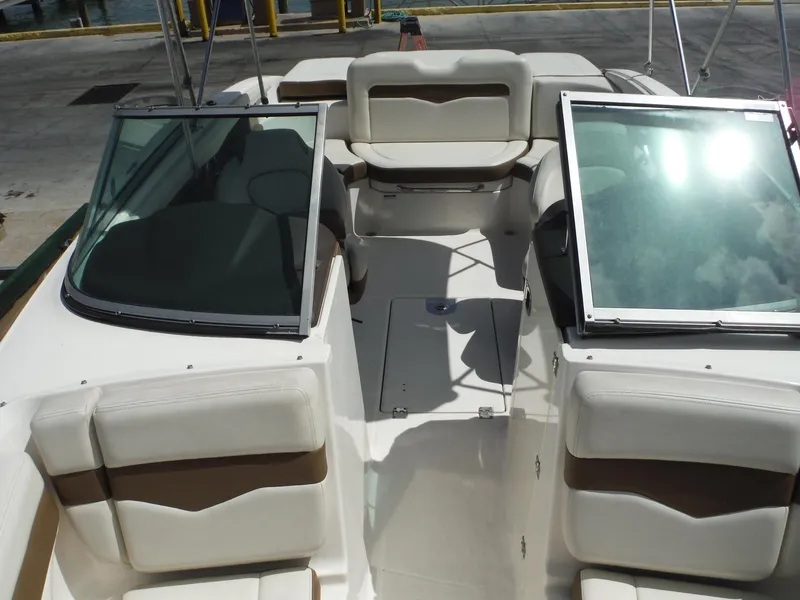 Slide: The Image of 2015 Chaparral 226 SSi boat interior with white and brown seating, docked at marina. - 20