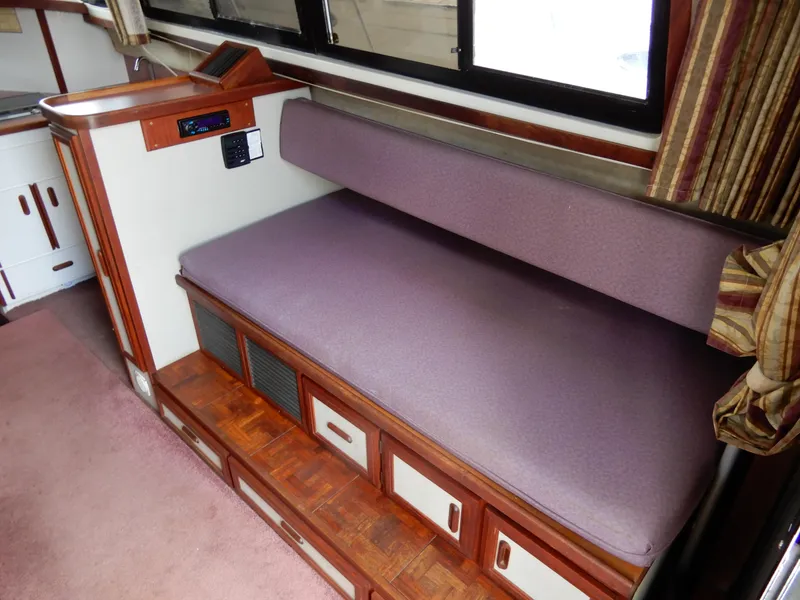 Slide: The Image of Interior of 1987 Carver 28 Mariner with purple seating and wooden storage drawers. - 26