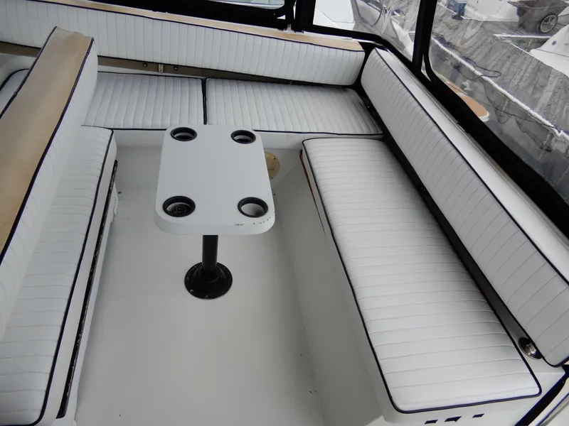 Slide: The Image of 1987 Carver 28 Mariner Voyager interior with white cushioned seating and a central table. - 16