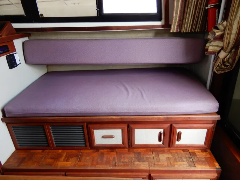 Slide: The Image of 1987 Carver 28 Mariner Voyager interior with purple cushion and wooden storage cabinets. - 31