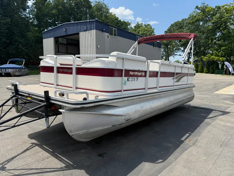 Slide: The Image of Pontoon boat Harris 200 Super Sunliner 2000 on trailer, parked near a building. - 4