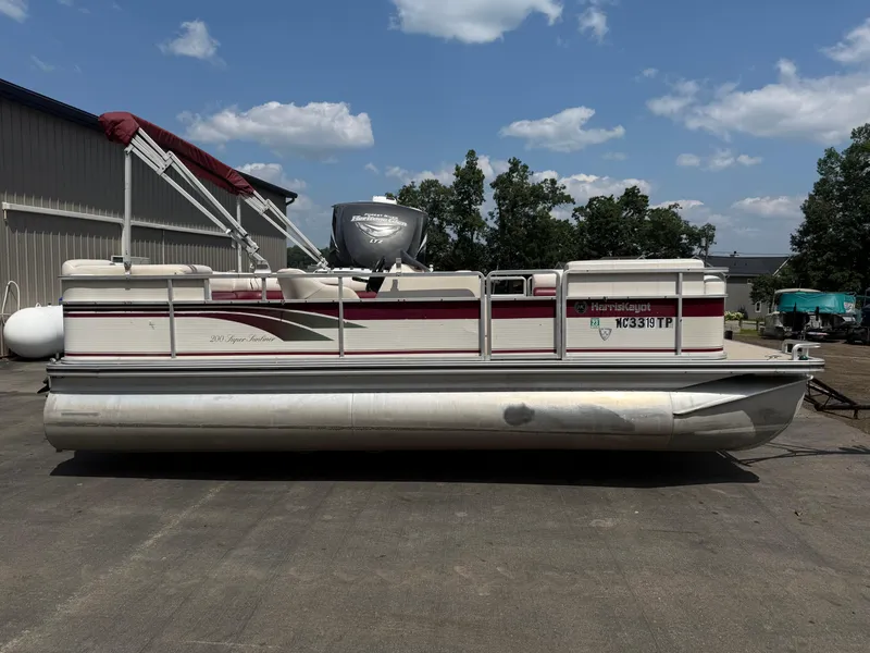 The Image of 2000 Harris 200 Super Sunliner pontoon boat parked outdoors under a blue sky. - 0