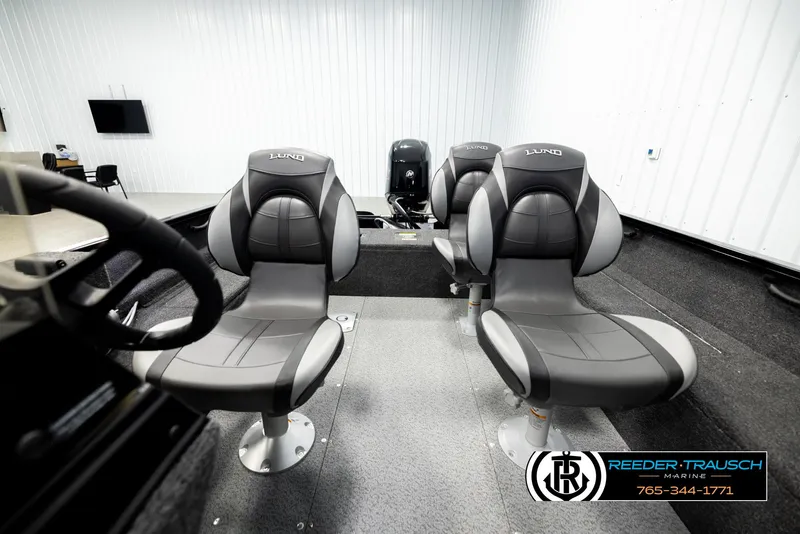 Slide: The Image of 2026 Lund 1650 Rebel XL SS boat interior with three gray seats in a showroom. - 12