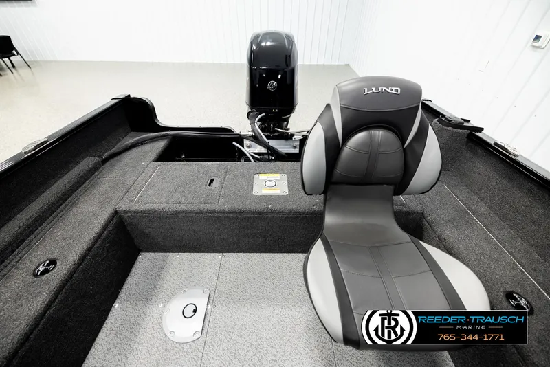 Slide: The Image of 2026 Lund 1650 Rebel XL SS boat interior with seating and motor, displayed in showroom. - 13