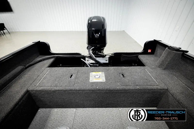 Slide: The Image of 2026 Lund 1650 Rebel XL SS boat interior with motor, gray carpet, and storage compartments. - 18