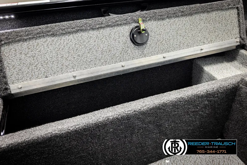 Slide: The Image of Storage compartment of 2026 Lund 1650 Rebel XL SS boat, featuring carpeted interior and secure latch. - 23