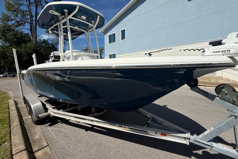 The Image of 2023 Tidewater 210 LXF boat on trailer, parked outdoors near a blue building. - 14