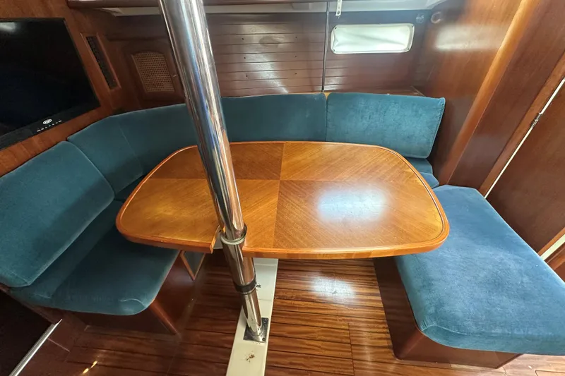 Slide: The Image of Interior of 1998 Beneteau Oceanis 352 with wooden table and blue seating. - 19