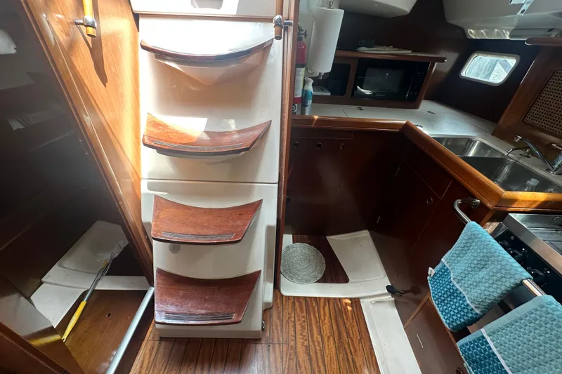 Slide: The Image of Interior of 1998 Beneteau Oceanis 352 sailboat with wooden cabinetry and kitchen amenities. - 20
