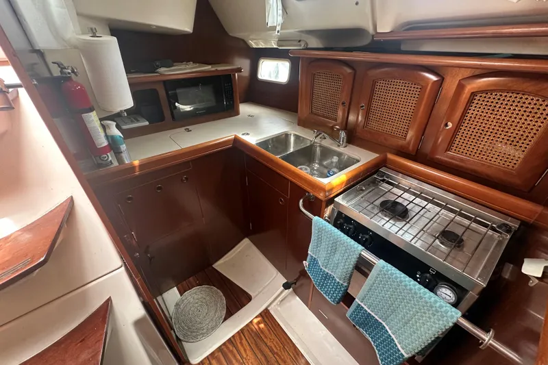 Slide: The Image of Cozy kitchen in 1998 Beneteau Oceanis 352 sailboat with stove, sink, and wooden cabinets. - 22