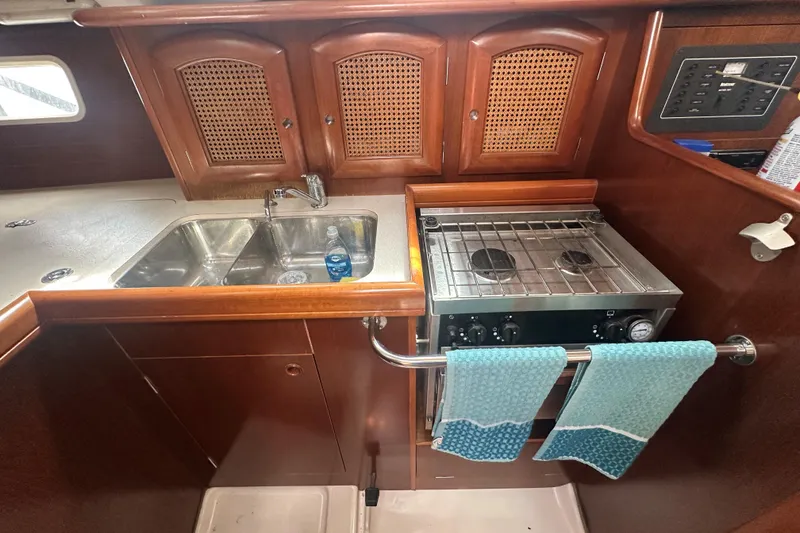 Slide: The Image of Galley of 1998 Beneteau Oceanis 352 with stove, sink, and wooden cabinetry. - 23