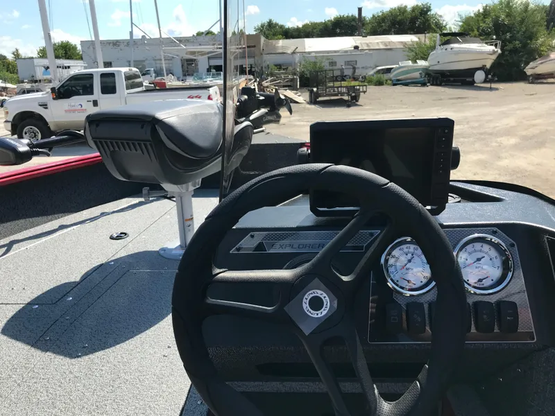 Slide: The Image of Red 2026 Lund 1800 Explorer SS boat on trailer, parked outside a metal building. - 12