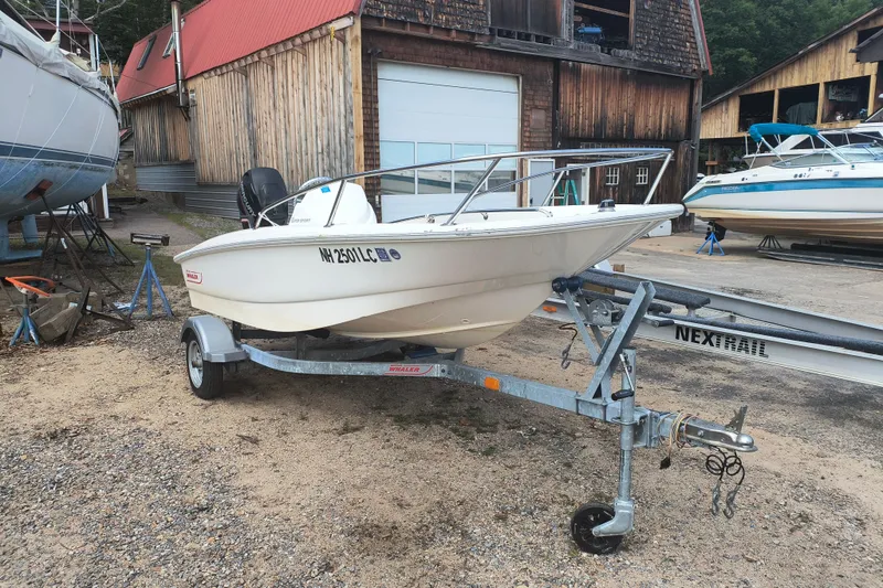 Slide: The Image of 2016 Boston Whaler 130 Super Sport boat on trailer in a rustic boatyard. - 1