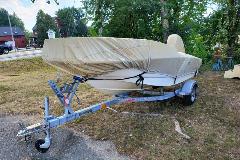 Slide: The Image of 2016 Boston Whaler 130 Super Sport boat covered on trailer, parked outdoors. - 10