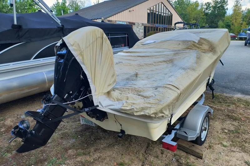 Slide: The Image of 2016 Boston Whaler 130 Super Sport boat covered on trailer, parked outdoors. - 12