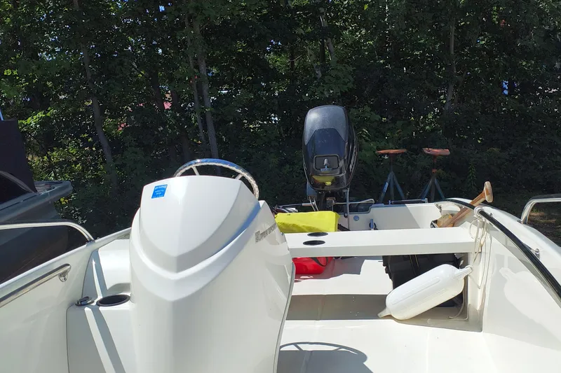 Slide: The Image of 2016 Boston Whaler 130 Super Sport boat interior with steering wheel and outboard motor. - 2