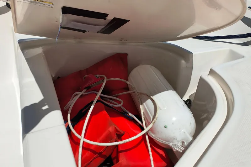 Slide: The Image of Open storage compartment on 2016 Boston Whaler 130 Super Sport with life jackets and fender. - 8