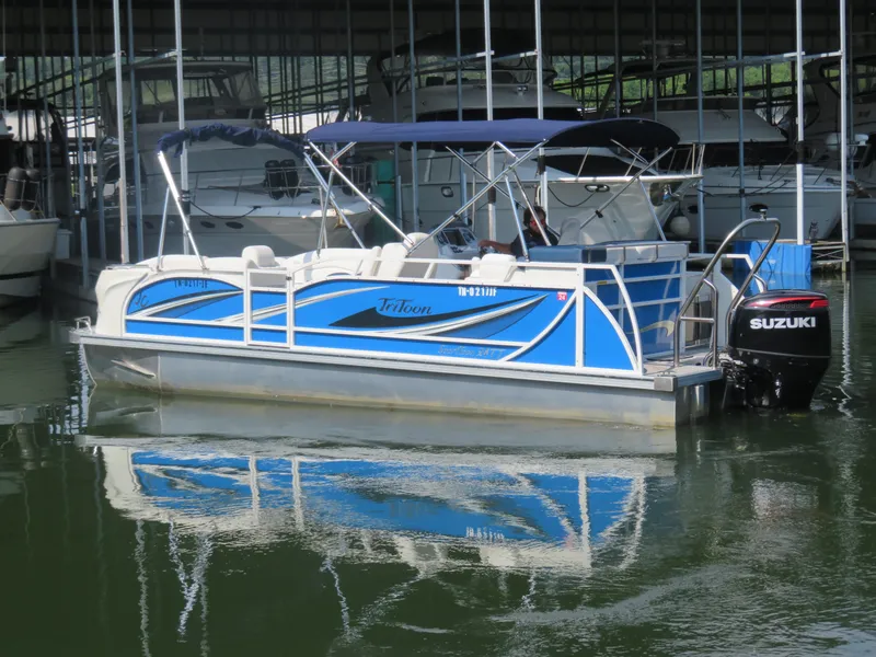 Slide: The Image of 2021 JC SportToon 24 TT CS pontoon boat docked with Suzuki outboard motor. - 2