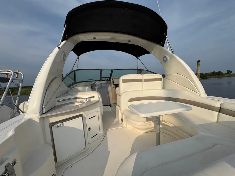Slide: The Image of 2003 Sea Ray 320 Sundancer boat interior with seating and table, under a black canopy. - 4