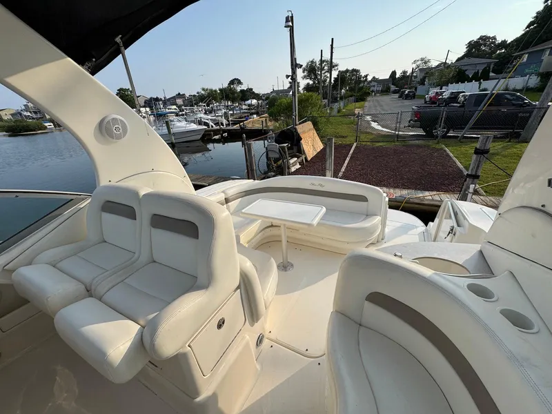 Slide: The Image of 2003 Sea Ray 320 Sundancer boat interior with white seating and table, docked at marina. - 7