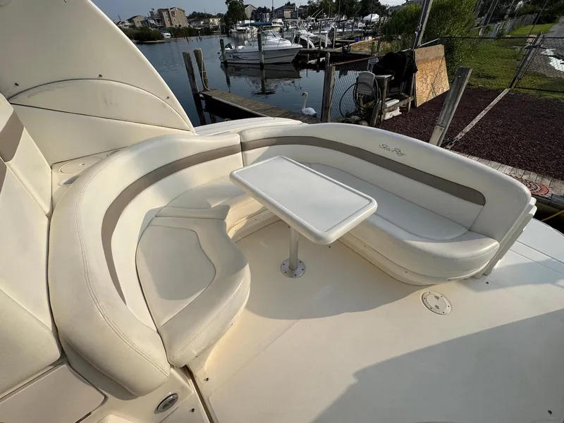 Slide: The Image of 2003 Sea Ray 320 Sundancer boat with white seating and table, docked at marina. - 8