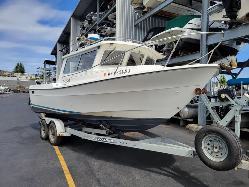 The Image of 1999 SeaSport 2400 XL Limited boat on trailer in marina storage area. - 1