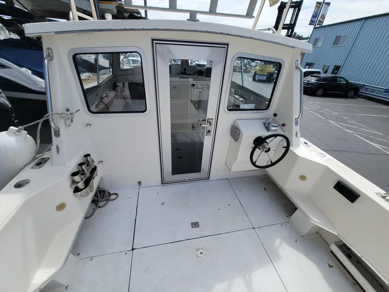 Slide: The Image of 1999 SeaSport 2400 XL Limited boat cockpit with steering wheel and cabin door. - 9