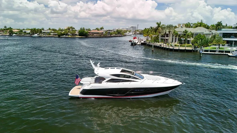 The Image of 2017 Sunseeker Predator 57 yacht cruising on a scenic waterway with luxury homes. - 0