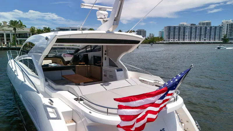 Slide: The Image of 2017 Sunseeker Predator 57 yacht with American flag, docked near waterfront buildings. - 18