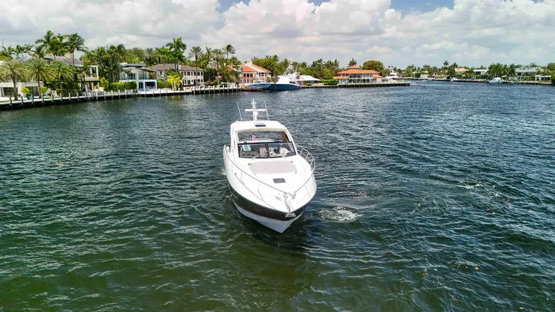 Slide: The Image of 2017 Sunseeker Predator 57 yacht cruising near waterfront homes under a cloudy sky. - 2