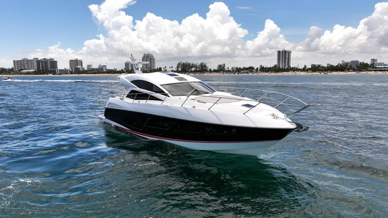 Slide: The Image of 2017 Sunseeker Predator 57 yacht cruising near a city shoreline under a blue sky. - 32