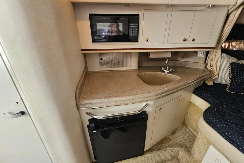 Slide: The Image of 2001 Sea Ray 290 Amberjack cabin with kitchenette, featuring microwave, sink, and compact fridge. - 20