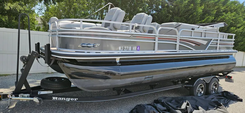 Slide: The Image of 2022 Ranger 223FC pontoon boat on trailer, parked outdoors. - 0