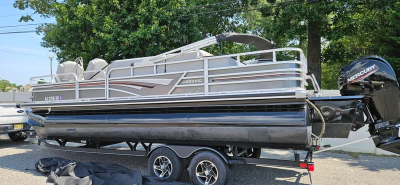 Slide: The Image of 2022 Ranger 223FC pontoon boat on trailer, featuring Mercury outboard motor, parked outdoors. - 1