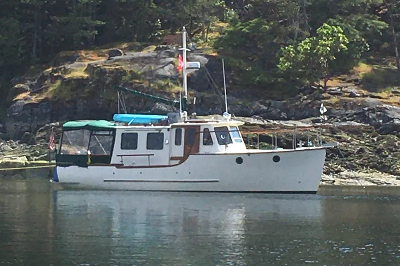 The Image of 2001 Maple Bay 32' Trawler anchored near rocky shoreline with trees. - 0