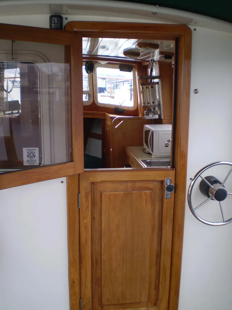 Slide: The Image of 2001 Maple Bay 32' Trawler interior with wooden door, steering wheel, and kitchenette. - 6