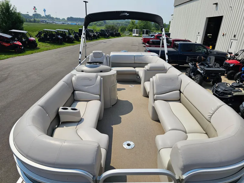 Slide: The Image of 2014 Bennington 2275 GL pontoon boat with spacious seating, parked near ATVs and a warehouse. - 6