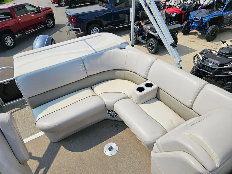 Slide: The Image of 2014 Bennington 2275 GL pontoon boat with beige seating and cup holders, parked near vehicles. - 8