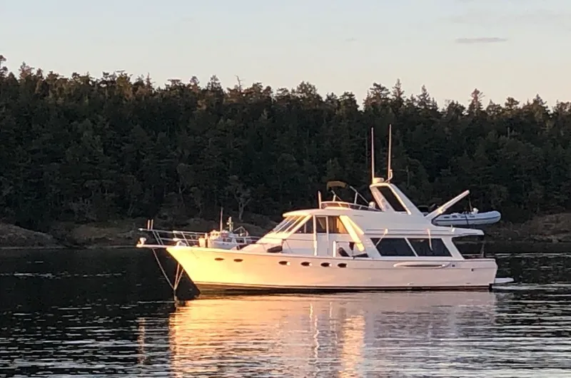 The Image of 2003 Meridian 490 Pilothouse Motor Yacht anchored on calm water at sunset. - 0