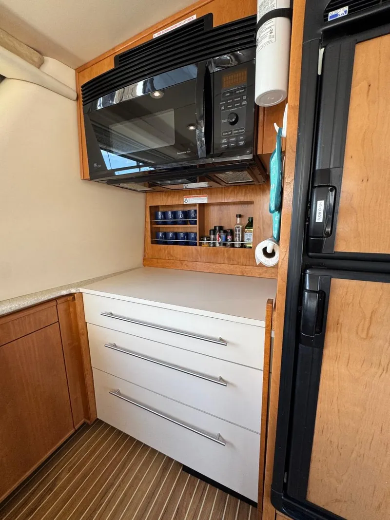 Slide: The Image of 2003 Meridian 490 Pilothouse Motor Yacht kitchen with microwave, drawers, and wooden cabinetry. - 12