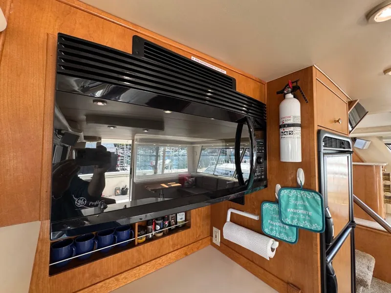 Slide: The Image of 2003 Meridian 490 Pilothouse Motor Yacht kitchen with microwave, fire extinguisher, and storage. - 14