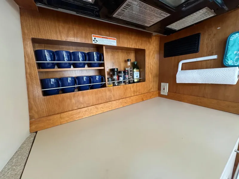 Slide: The Image of 2003 Meridian 490 Pilothouse Motor Yacht kitchen with blue mugs and spices on wooden shelves. - 15
