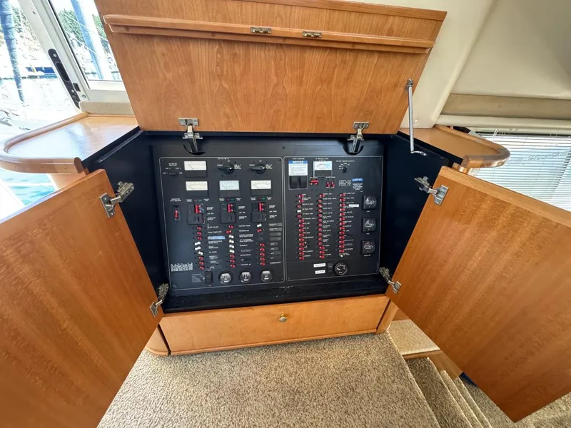 Slide: The Image of Electrical panel inside 2003 Meridian 490 Pilothouse Motor Yacht, with open wooden cabinet doors. - 28