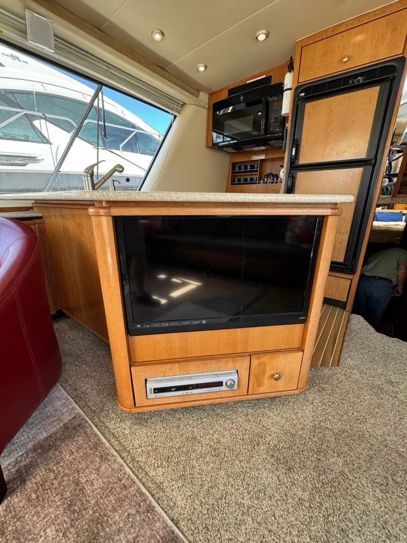Slide: The Image of 2003 Meridian 490 Pilothouse Motor Yacht interior with TV and kitchen amenities. - 7