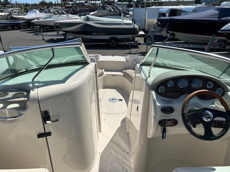 Slide: The Image of 2004 Sea Ray 220 Sundeck boat interior with dashboard and seating, parked among other boats. - 10