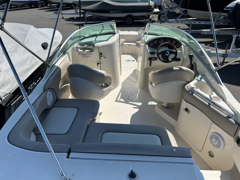 Slide: The Image of 2004 Sea Ray 220 Sundeck interior with seating and steering wheel, parked in a marina. - 14
