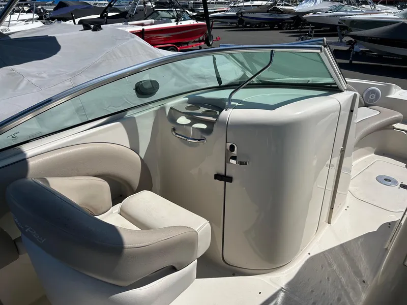 Slide: The Image of 2004 Sea Ray 220 Sundeck interior with seating and helm, docked among other boats. - 9
