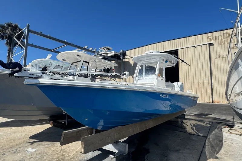 Slide: The Image of 2021 Everglades 243 CC boat in blue, docked at a marina under clear skies. - 1