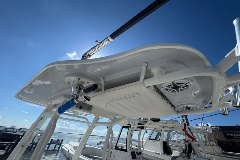 Slide: The Image of 2021 Everglades 243 CC boat with T-top and rod holders, docked under clear blue sky. - 18