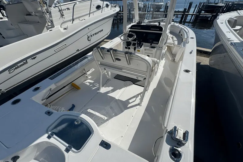 Slide: The Image of 2021 Everglades 243 CC boat interior with console and seating, docked beside other boats. - 21
